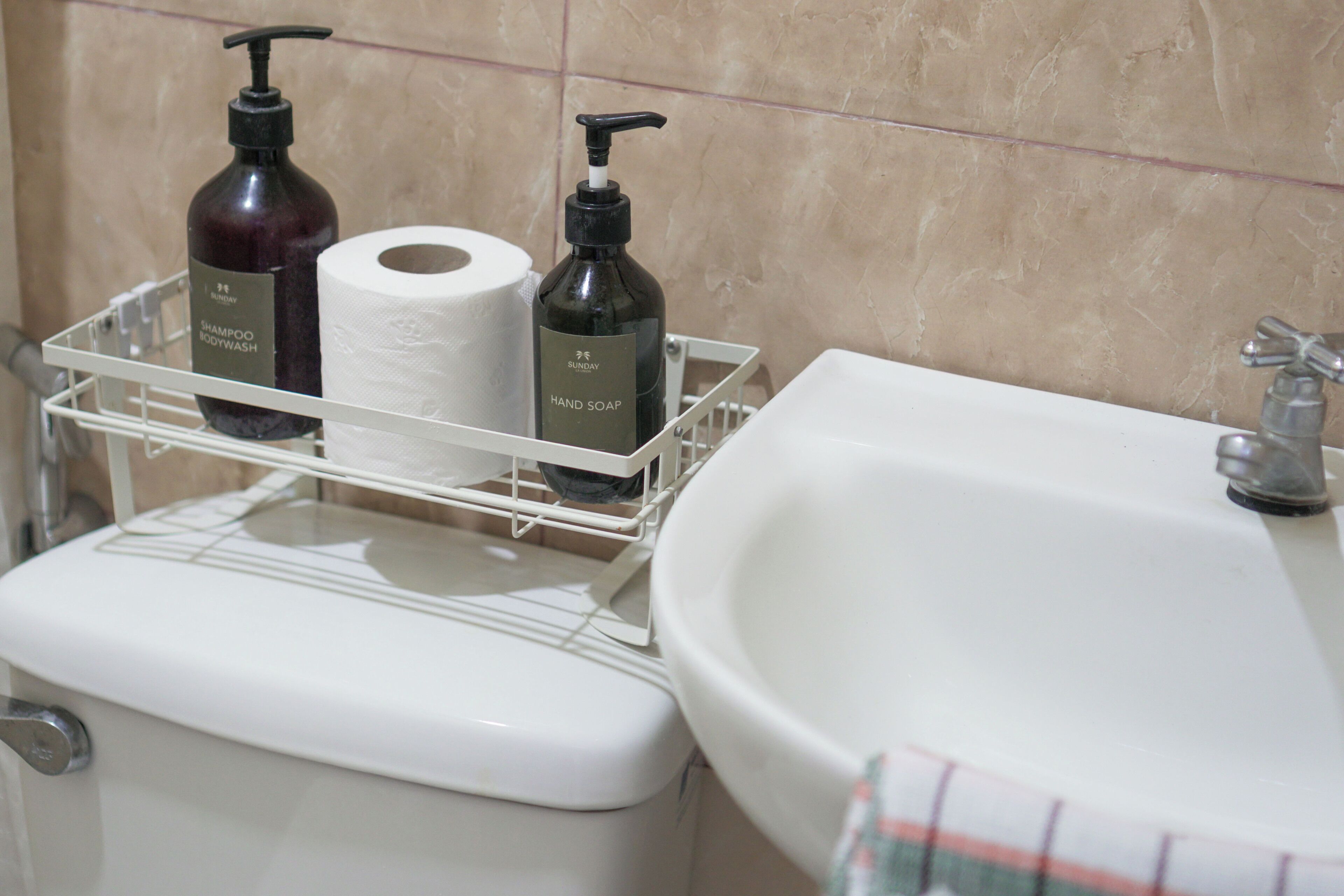 Une salle de bain équipée de toilettes, d’un lavabo et d’une étagère où sont rangés les articles de toilette.