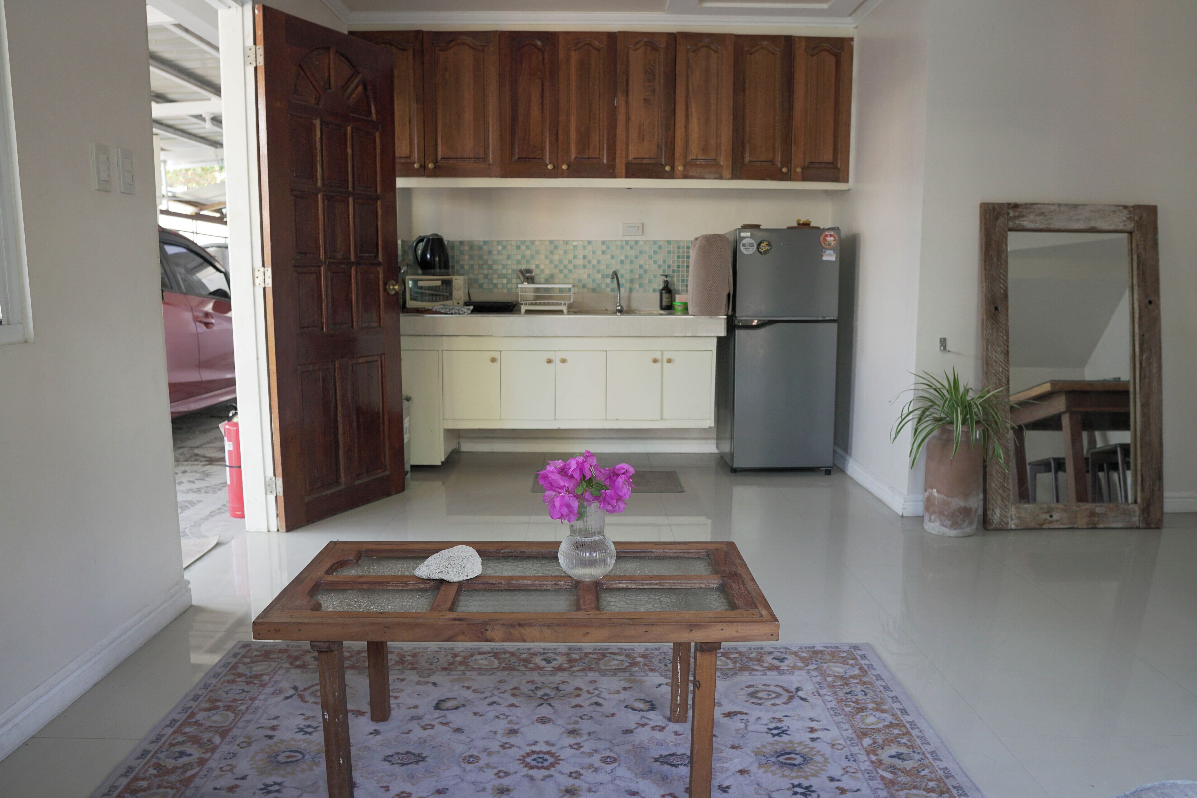 Uma cozinha com armários de madeira, geladeira, micro-ondas e uma mesa com um vaso de flores.