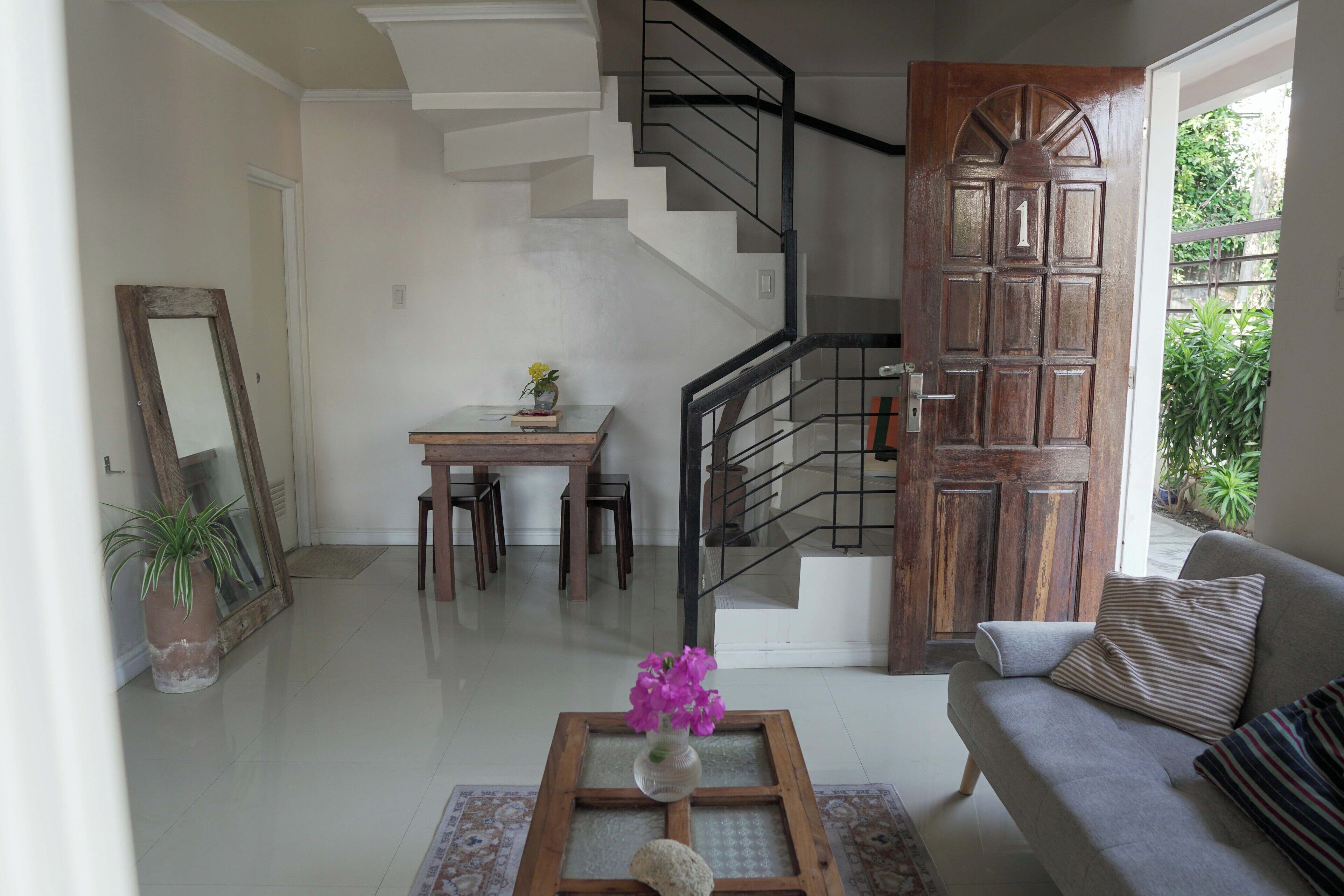 A living room with a staircase, a dining area, and a sofa.