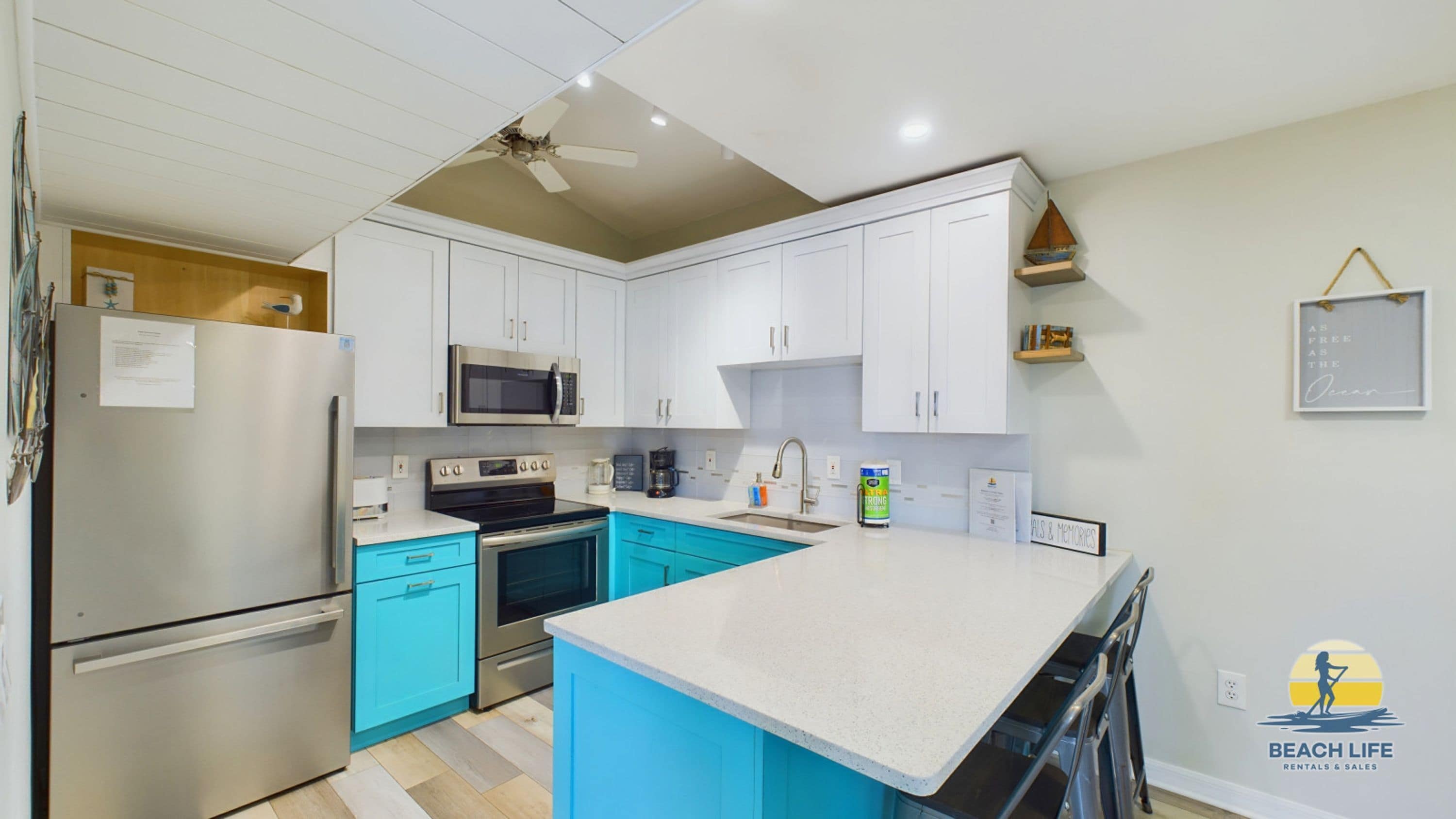 A modern kitchen with white cabinets, a stainless steel refrigerator, a microwave, and a stove.