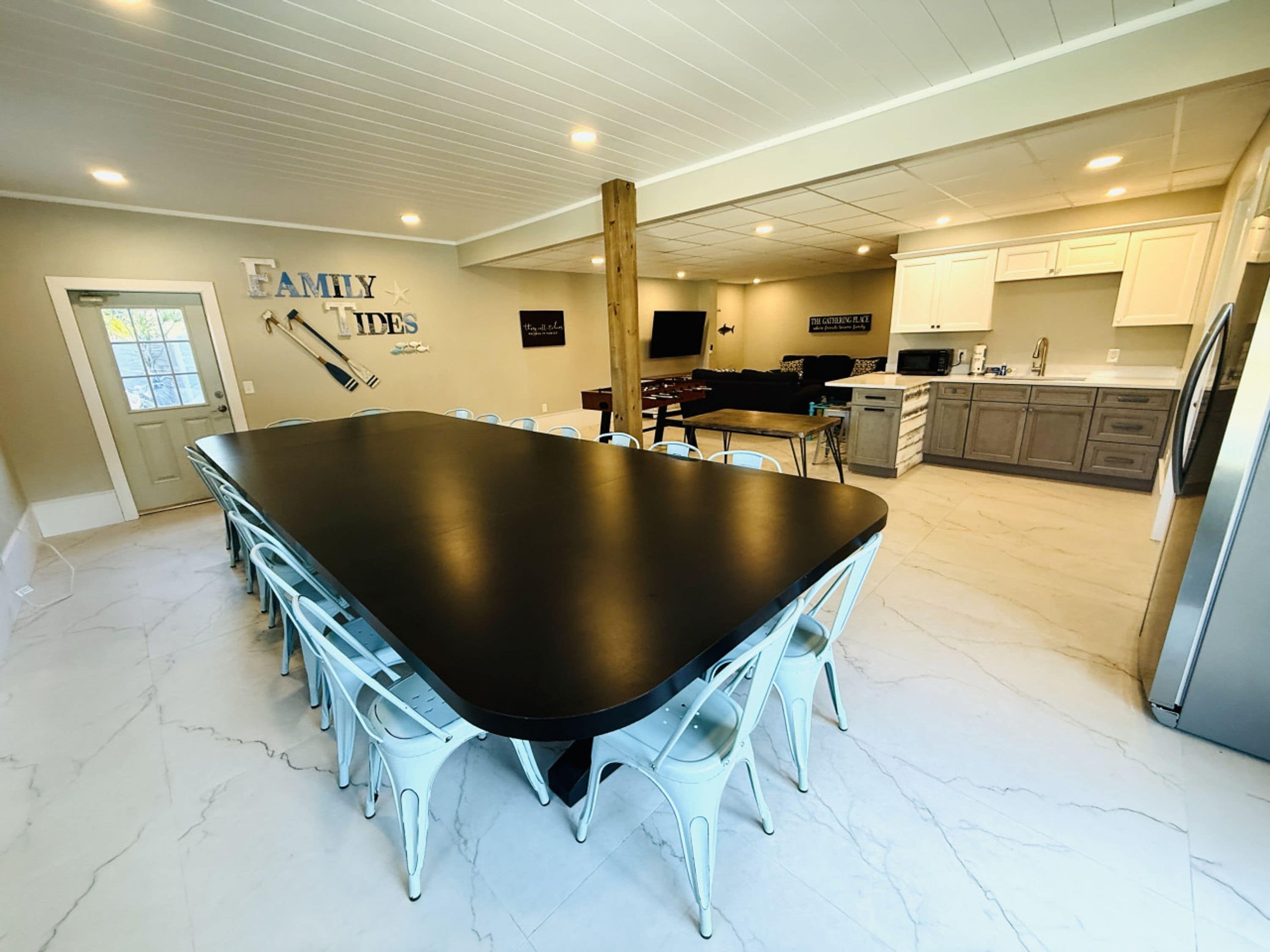 A spacious kitchen with a large island, white cabinetry, and a dining area with a long table and chairs.