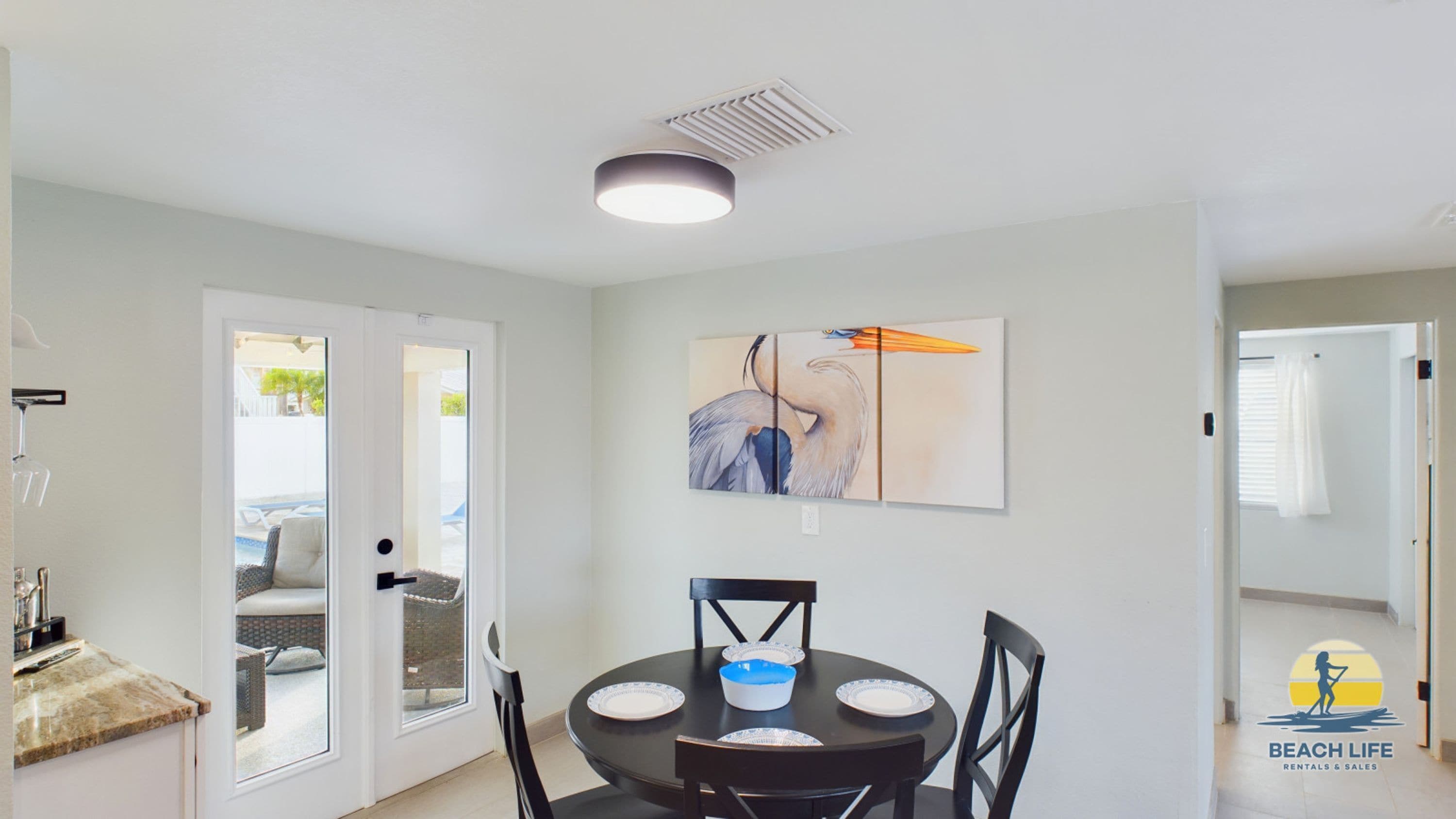 A dining area with a round table, chairs, and a wall-mounted painting.