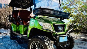 Un carrello da golf verde con copertura, pneumatici larghi e una targa ben visibile con il numero 'G2'.