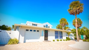 A two-story house with a white exterior, a garage, and a front porch. - Anna Maria Oasis Heated Pool Spa Putting Green Golf Cart Incl Game Rm Sundeck Tiki bar Sleeps 12 (Holmes Beach)