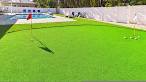 Ein gepflegter Bereich mit Kunstrasen, einem Pool und Liegestühlen.