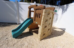 Ein Sandspielbereich mit Rutsche und Klettergerüst.
