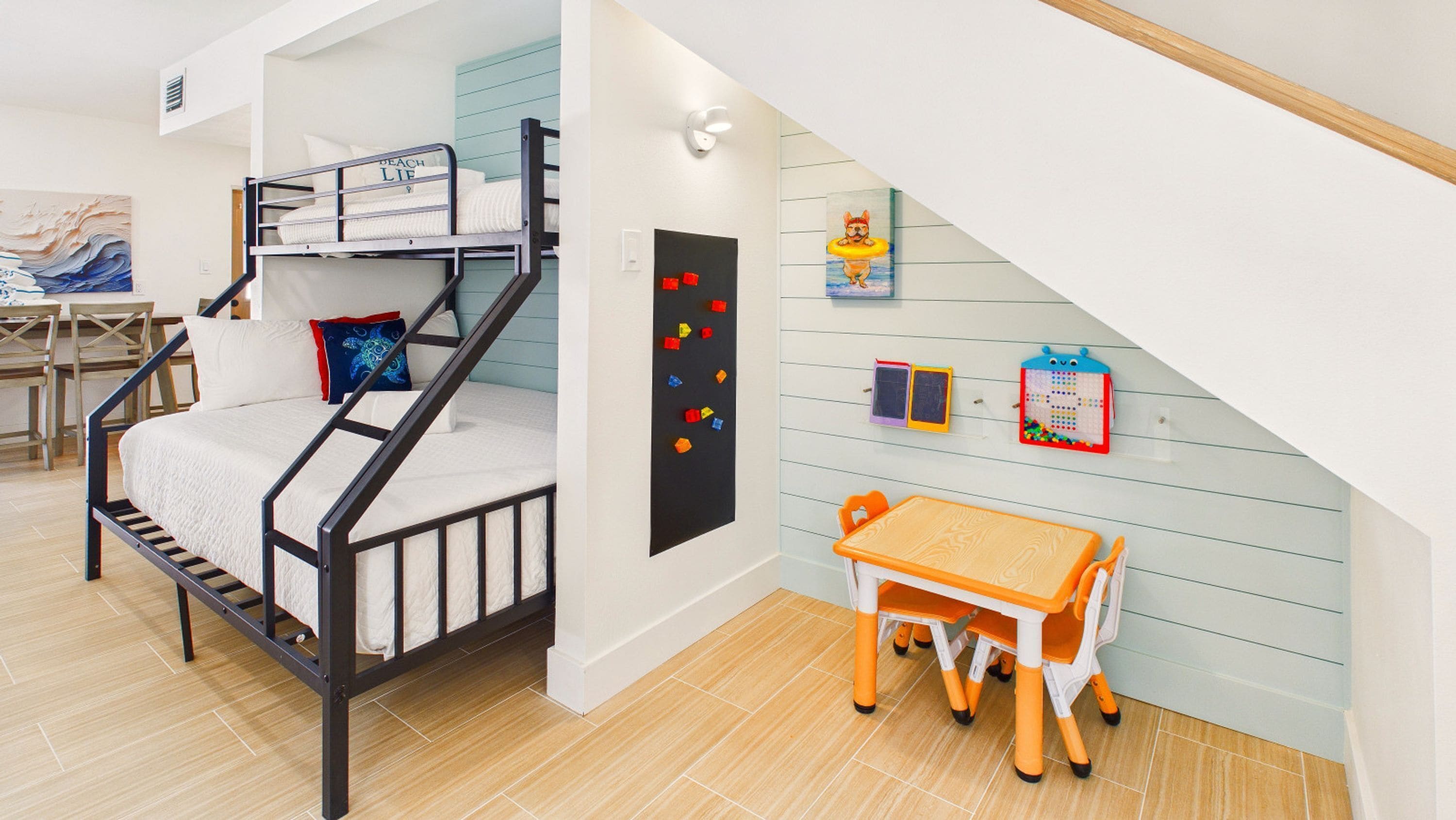 A child's room with bunk beds, a desk, and educational toys on the wall.