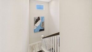 A staircase with a white railing and a painting on the wall. - Siesta Sunsets Tropical Siesta Key Getaway Private Heated Pool Fire Pit Walk to Beach Village (Siesta Key)