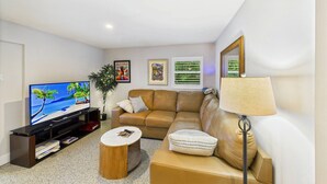 A living room with a television, sofa, coffee table, and a lamp. - Siesta Sunsets Tropical Siesta Key Getaway Private Heated Pool Fire Pit Walk to Beach Village (Siesta Key)