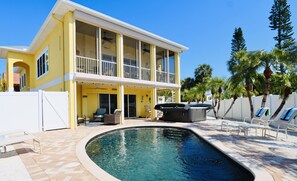 A two-story house with a swimming pool, outdoor furniture, and palm trees. - Barefoot Bliss 3-min Walk to Beach Heated Pool Spa Golf Cart Gulf Views (Holmes Beach)