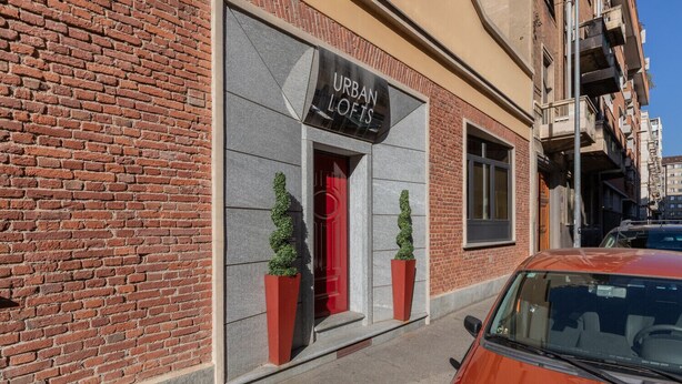 A brick building with a sign reading 'URBAN LOFTS' and two potted plants on the sidewalk. - Loft Lingotto by Wonderful Italy (Turin)