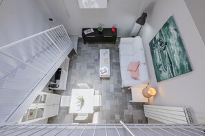 A modern interior with a white staircase, a white sofa, a coffee table, and a painting on the wall. - Loft Lingotto by Wonderful Italy (Turin)