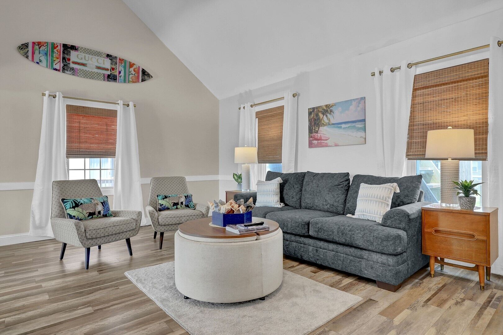 A living room with a grey sofa, armchairs, a coffee table, and a wooden side table.