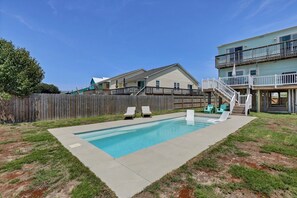 Un jardin avec une piscine, des chaises longues et une terrasse en bois.