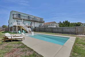 Ein zweistöckiges Haus mit Swimmingpool, überdachter Terrasse und Holzzaun.