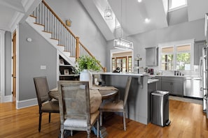 A modern kitchen with a central island, wooden flooring, and a staircase with a wooden railing. - McLemore Resort - 68 Founder Path - Walking distance to Range and Clubhouse (Rising Fawn)