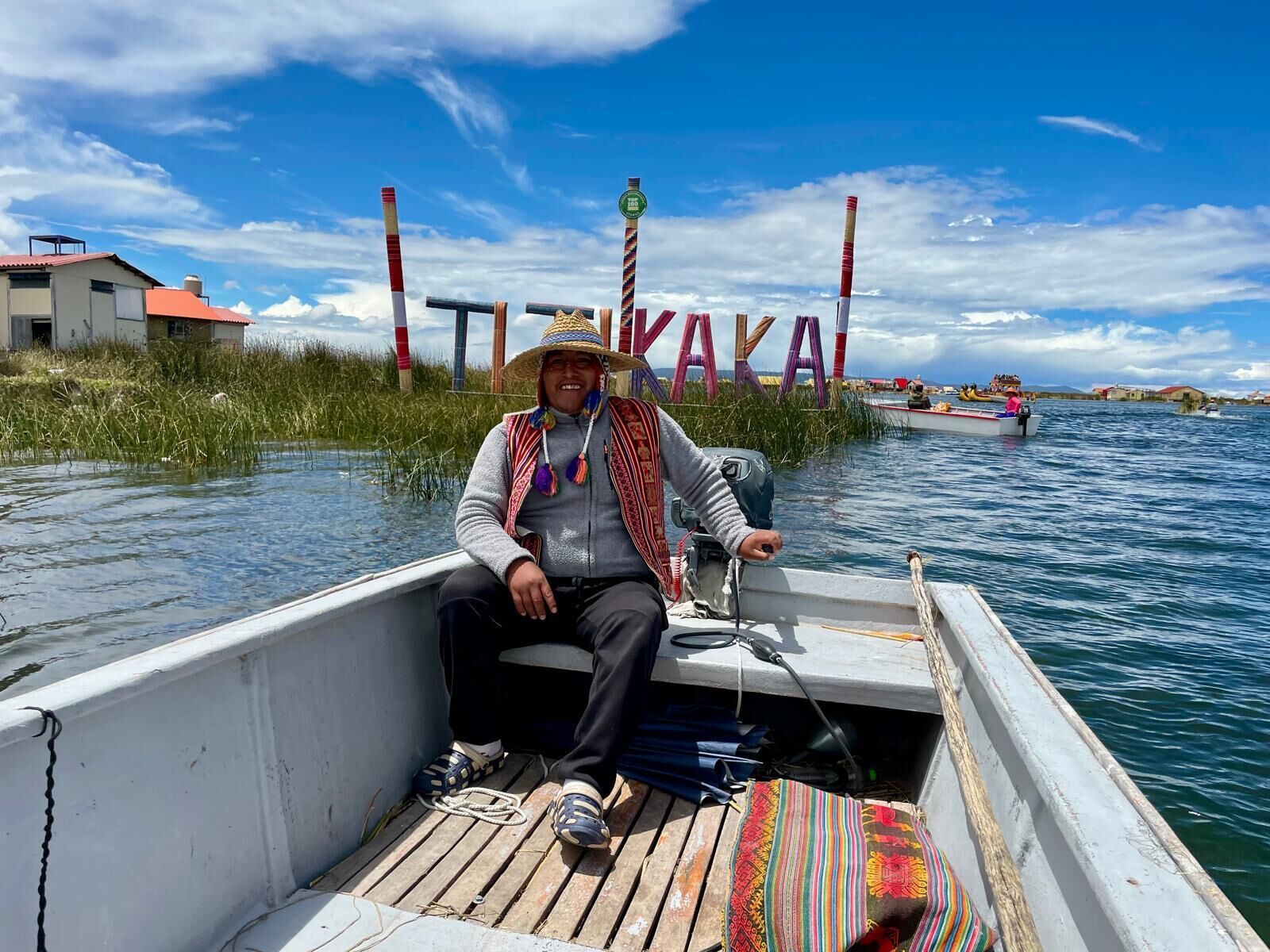 A person seated on a boat with a view of a waterway and a building with the word 'TIKAYAK' in the background.