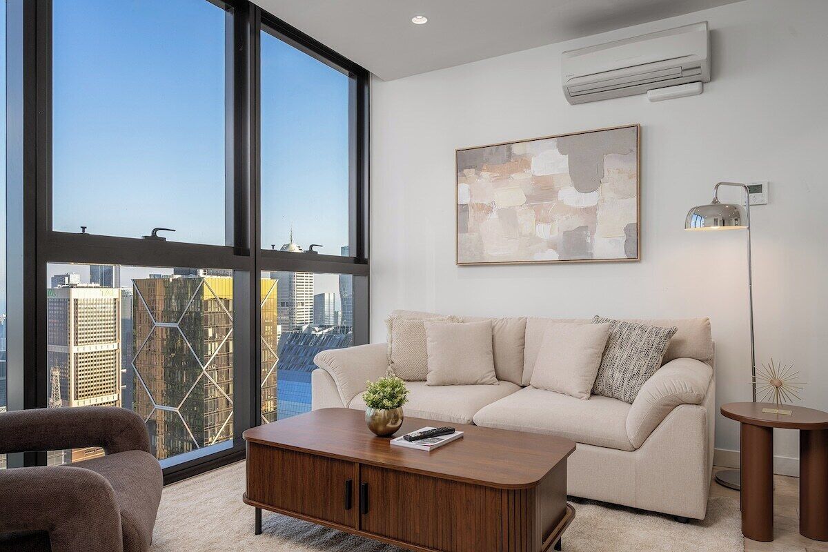 A modern living room with a large window, a sofa, a coffee table, and a floor lamp.