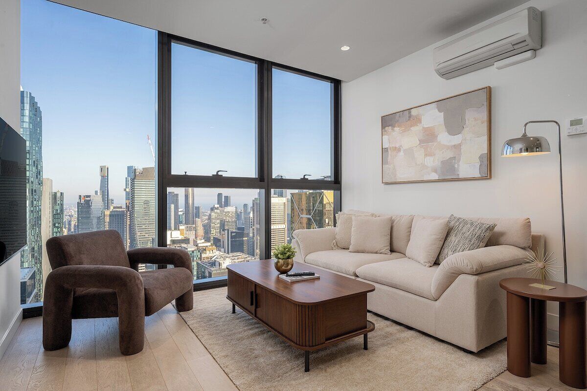 Una sala moderna con vista a la ciudad, un sofá, una silla, una mesa de centro y una lámpara.