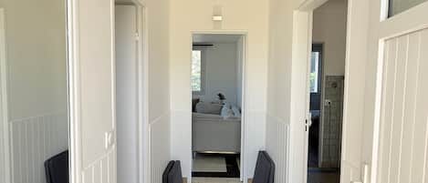 Un couloir carrelé mène à une chambre à coucher qui contient un lit et une fenêtre.