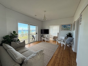 Ein geräumiges Wohnzimmer mit einer großen Couch, einem Fernseher und Blick ins Freie.