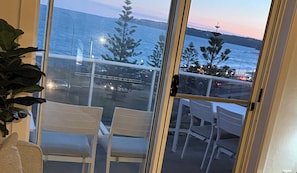 A balcony with two chairs and a view of the sea at dusk. - Alice’s by the Beach, Bar Beach with Beach View, close to town, off street park (Bar Beach)