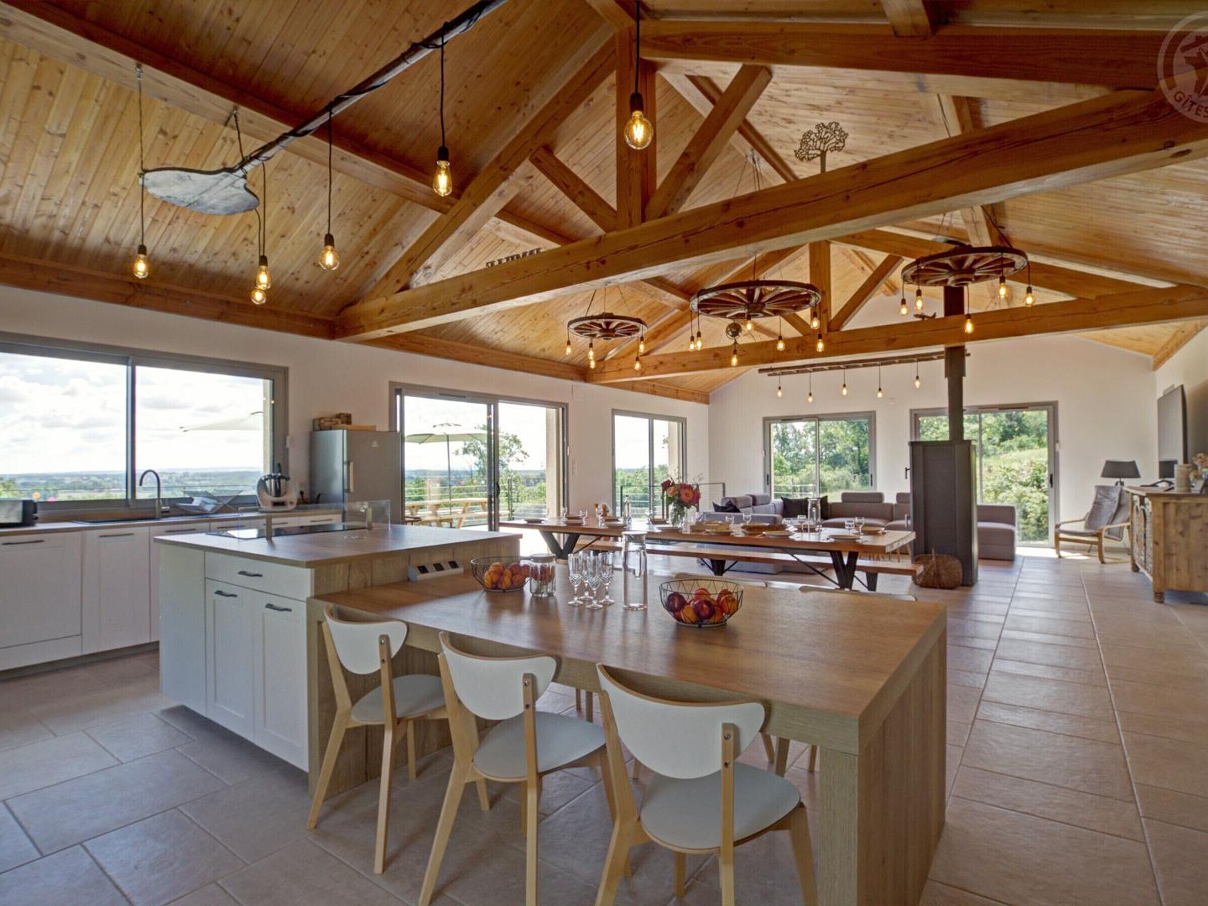 A spacious kitchen with a large island, wooden beams, and pendant lighting.