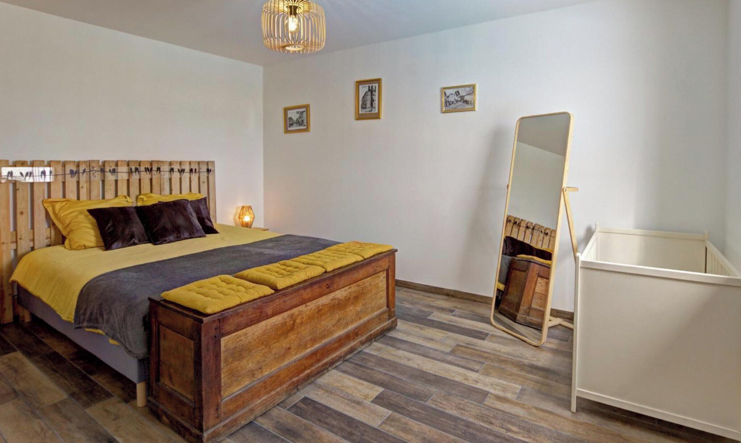 Une chambre à coucher avec un lit en bois, une table de chevet, un miroir et une étagère fixée au mur.