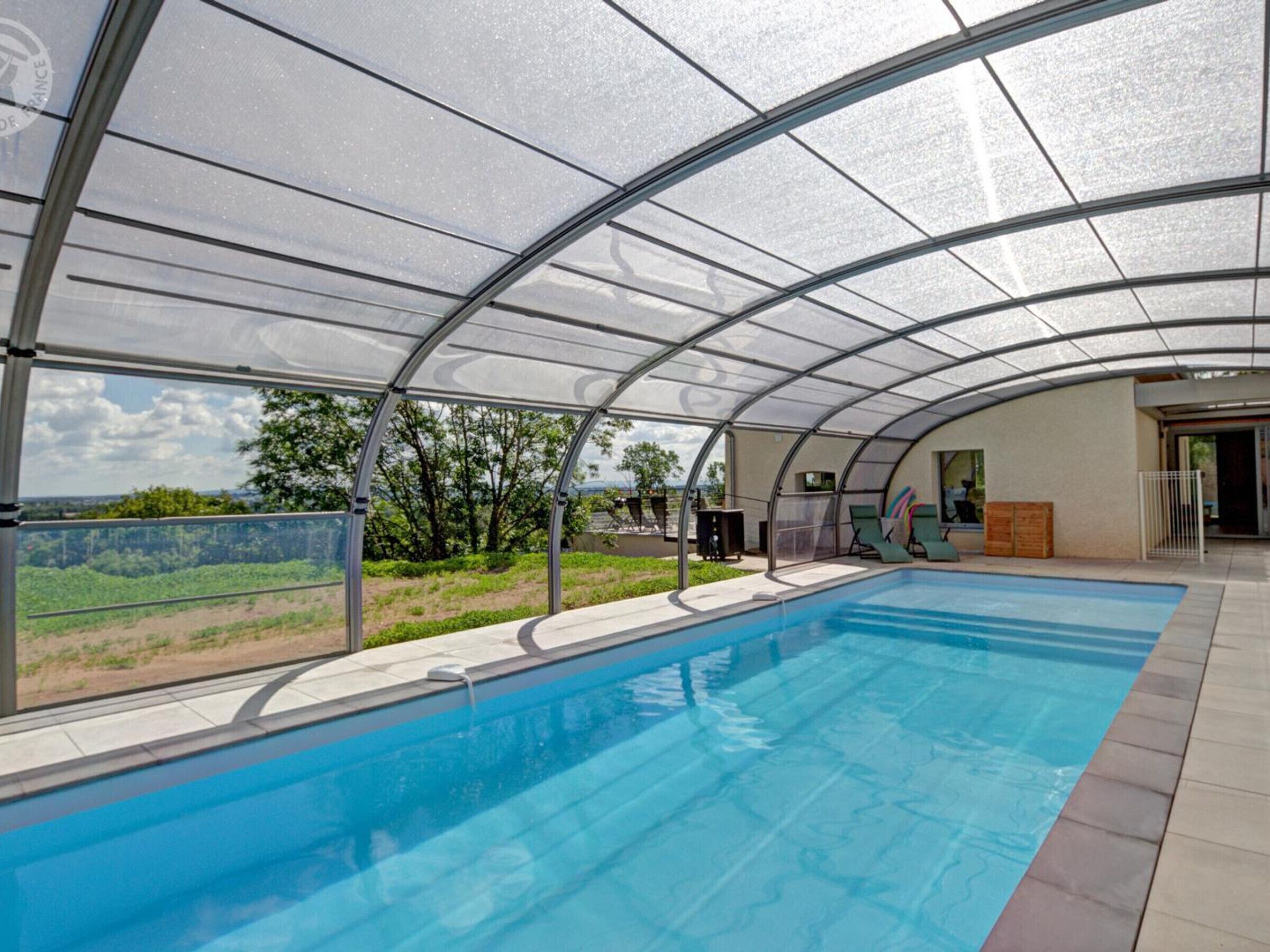 A covered swimming pool with a view of the landscape.