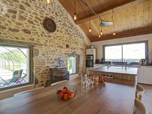 Una cucina con pareti in pietra, soffitto in legno e un'ampia finestra.