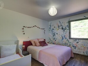 Una camera da letto con un letto, un comodino e una finestra vista verde.