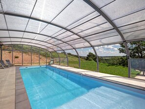 A covered swimming pool with a view of the surrounding landscape.