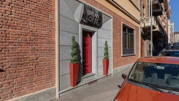 Un edificio de ladrillo con un letrero que dice 'URBAN LOFTS' y dos macetas con plantas en la acera.