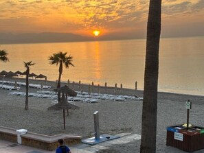 A beach scene with sun umbrellas, lounge chairs, and a trash bin. - Elegant apartment, sea view, AC - 4 guests (Torremolinos)