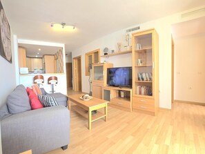 Ein Wohnzimmer mit einer Couch, einem Couchtisch, einem Fernseher und einem Bücherregal.