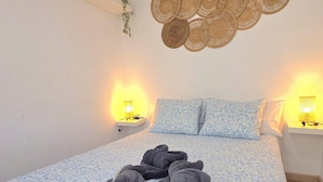 Un dormitorio con una cama, dos mesitas de noche con lámparas y un cuadro colgado en la pared.