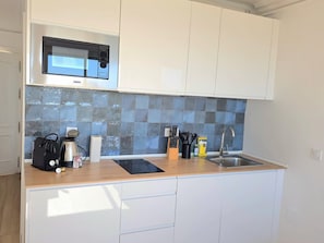 Eine kleine Küche mit Mikrowelle, Spüle und einer Holz Arbeitsplatte.