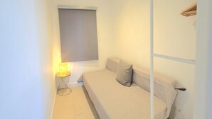 A small, clean room with a bed, a bedside table with a lamp, and a window with a blind. - Apartment sea view, AC & WiFi - 6 guests (Torremolinos)