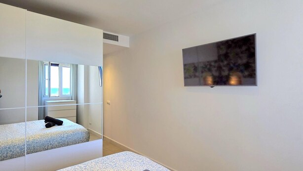 A hotel room with a bed, a mirror, a television, and a window with a view. - Apartment sea view, AC & WiFi - 6 guests (Torremolinos)