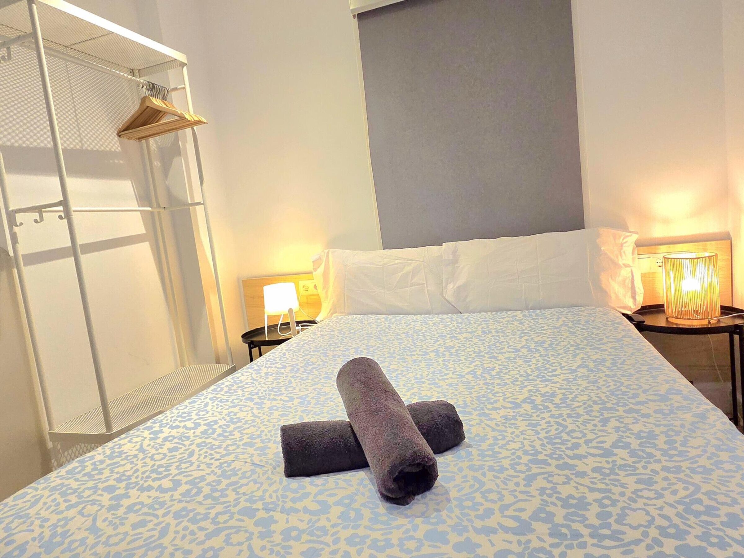 Ein Hotelzimmer mit Bett, Nachttisch, Lampe und Kleiderschrank.