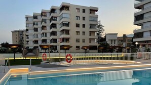 A swimming pool with a surrounding fence and lifebuoys, set against a backdrop of multi-story residential buildings. - Apartment sea view, AC & WiFi - 6 guests (Torremolinos)