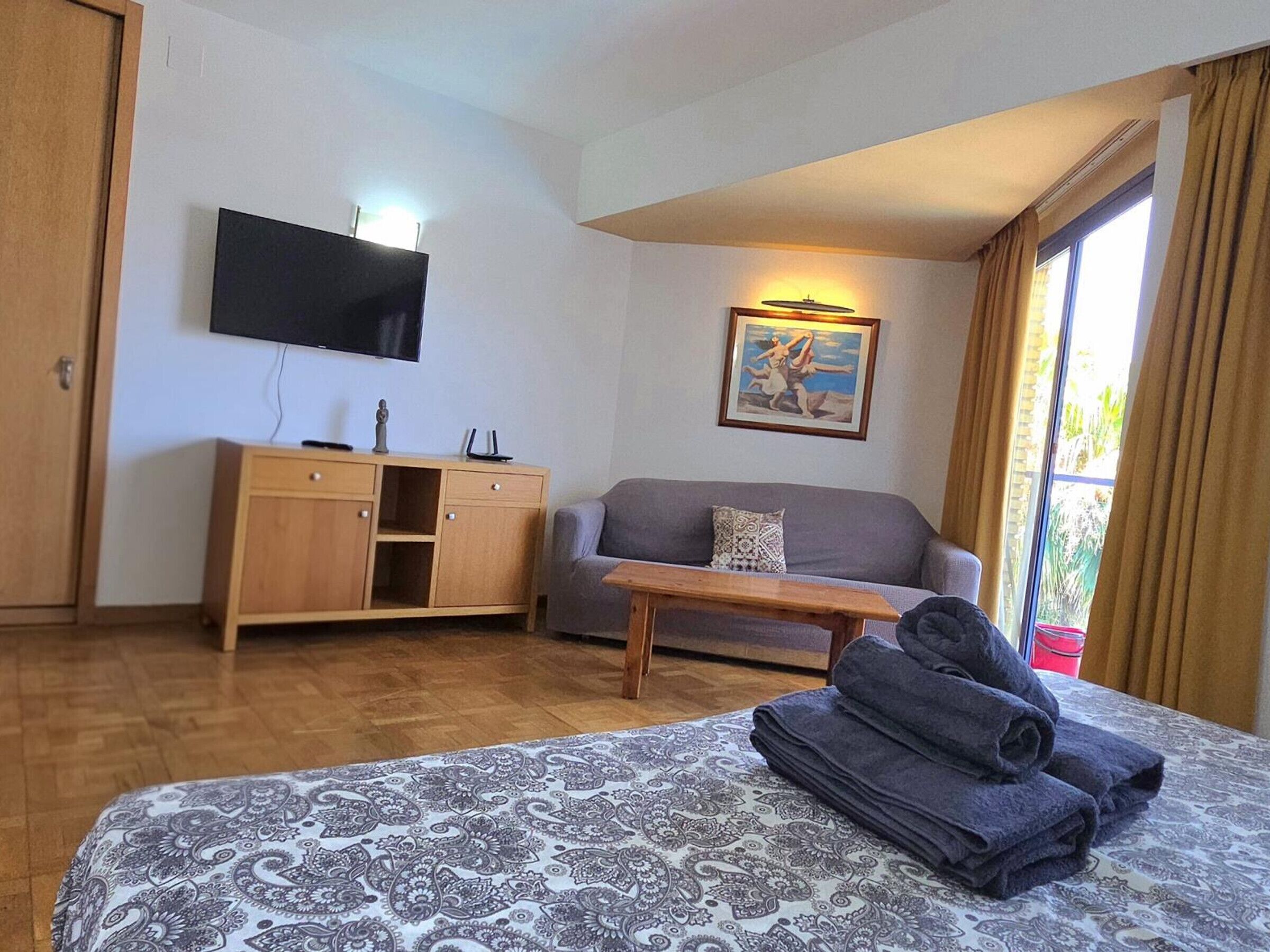 Una habitación de hotel con una cama, un sofá, un escritorio, un televisor y un cuadro.