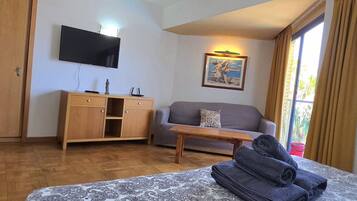 Una habitación de hotel con una cama, un sofá, un escritorio, un televisor y un cuadro.