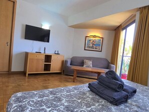 Una habitación de hotel con una cama, un sofá, un escritorio, un televisor y un cuadro.