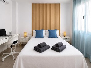 A hotel room with a bed, two bedside tables, a desk with a laptop, a chair, and a window with curtains. - New central apartment - 2 guests (Benalmádena)