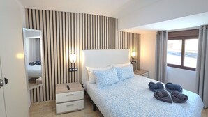 Ein Hotelzimmer mit Bett, Nachttischen, einem Spiegel und einem Fenster mit Vorhängen.