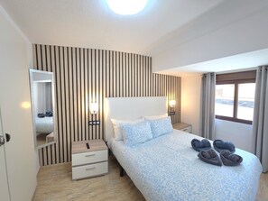 Ein Hotelzimmer mit Bett, Nachttischen, einem Spiegel und einem Fenster mit Vorhängen.