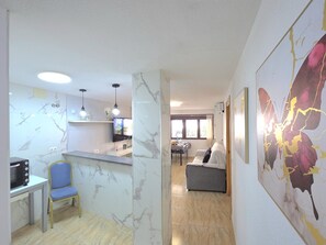 A modern kitchen with a marble backsplash, a dining area with a table and chairs, and a living room with a sofa and a large painting. - Central apartment with pool - 4 guests (Torremolinos)