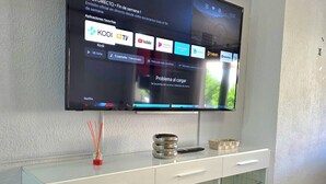 Ein Flachbildfernseher ist an einer Wand über einem weißen Schrank mit Glastüren angebracht.