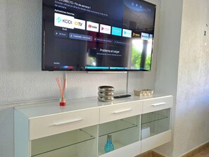 Ein Flachbildfernseher ist an einer Wand über einem weißen Schrank mit Glastüren angebracht.